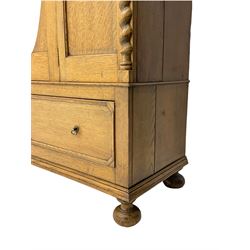 Early 20th century oak wardrobe, projecting cornice of blind fret-work frieze, oval bevel edge mirror door, half spiral turned pilasters, drawer to base with mouldings, on turned bun feet