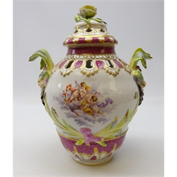  Late 19th/ early 20th century Berlin porcelain pot pourri vase and cover, painted with putti and floral vignettes, two mask and leaf moulded handles below a floral encrusted finial, underglaze blue scepter mark, H29cm   