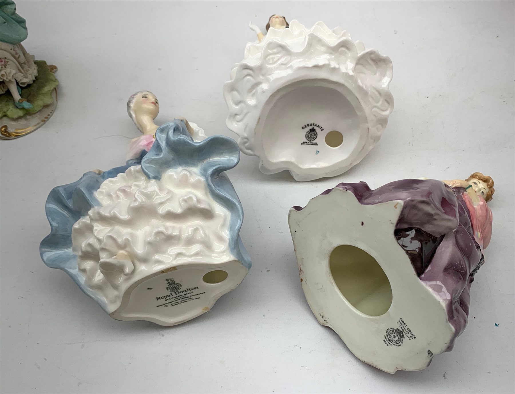 A group of figurines, comprising two boxed Spode Pauline Shine examples, Lily and Olivia (one a/f), a Royal Douton figurine First Dance modelled by F G Doughty, a further Royal Doulton figurine, Debutante, a Royal Doulton figurine, Southern Belle HN2425, and an unmarked continental figurine. 