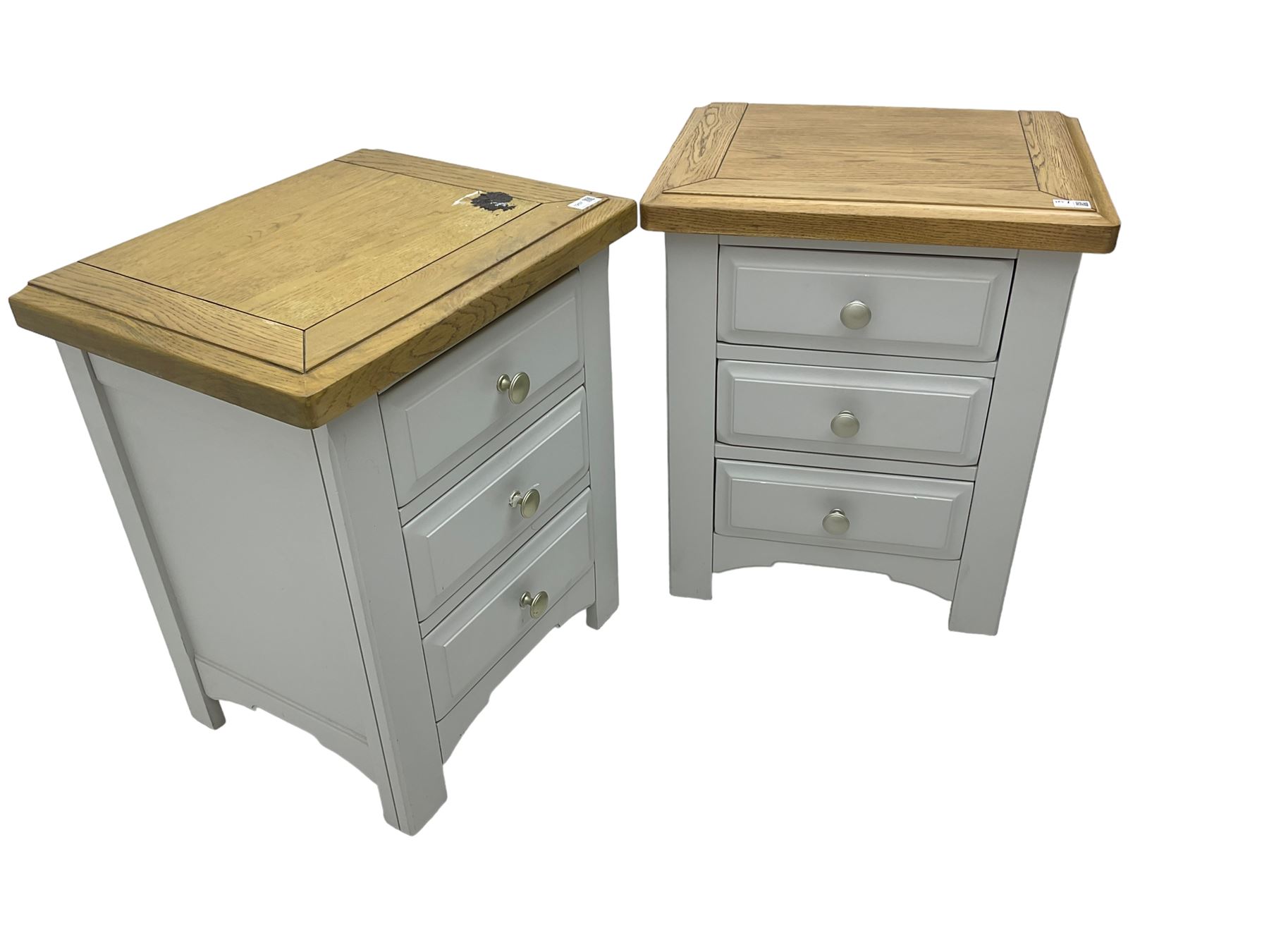 Pair of painted bedside chests with oak top, fitted with three drawers, raised on square supports with shaped apron, in cream finish