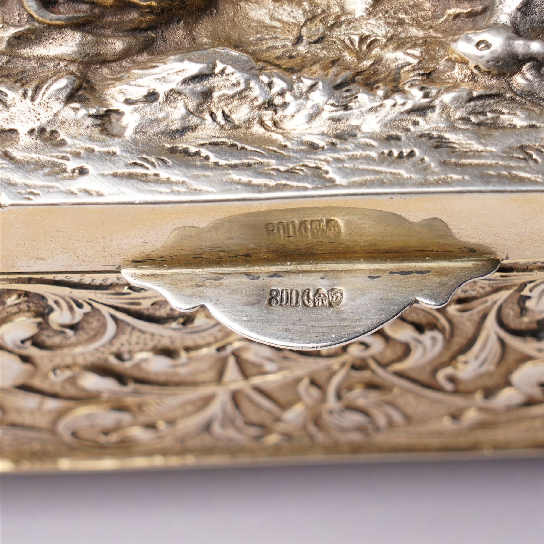 German 800 standard silver gilt and ivory mounted box, the hinged cover embossed and chased with an allegorical feasting scene, the sides with floral decoration, on four cast lion feet 21cm x 16cm x 8cm Maker Ludwig Neresheimer, Hanau circa 1900 This item has been registered for sale under Section 10 of the APHA Ivory Act