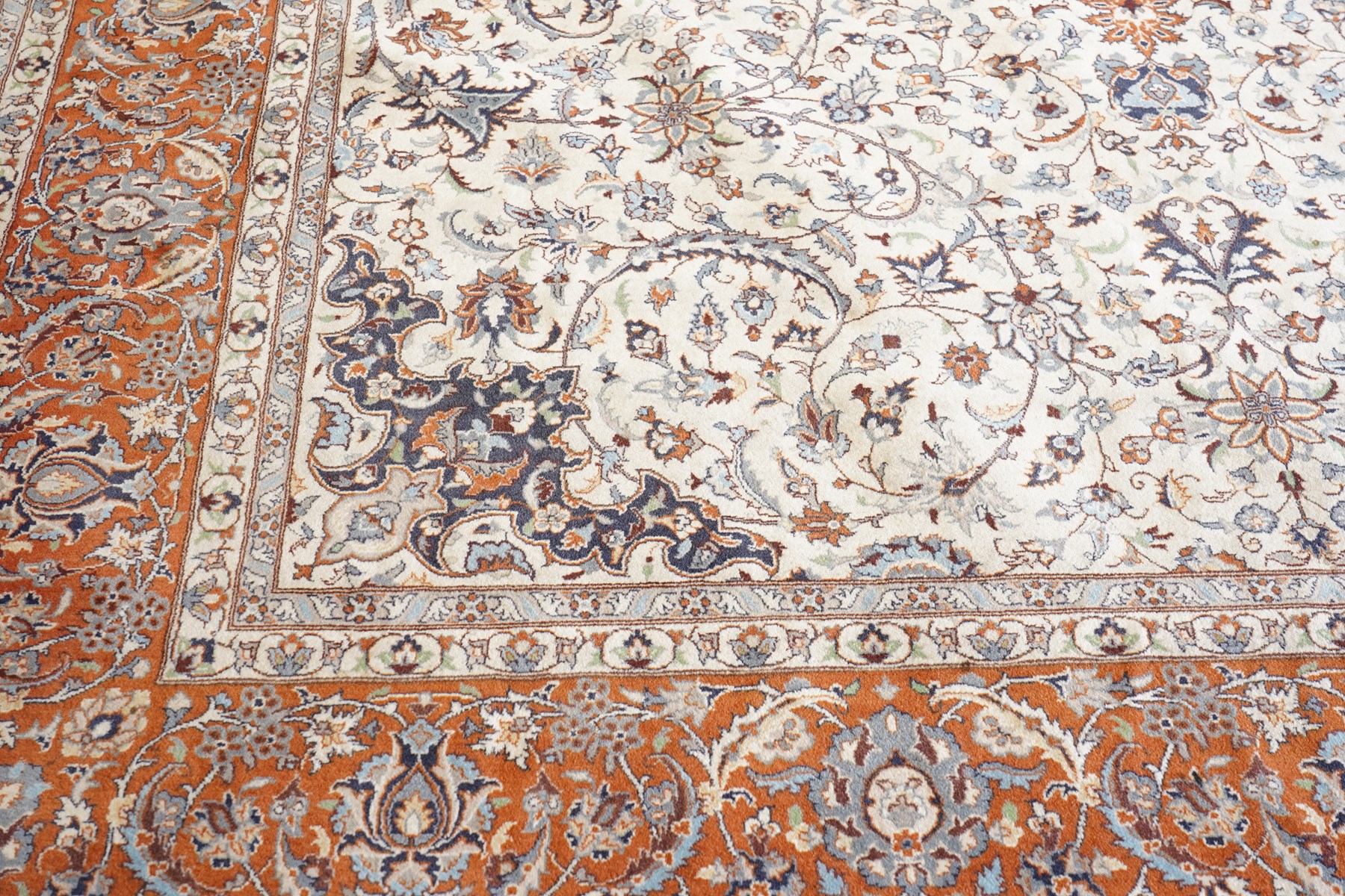 Persian ivory ground Kashan carpet, the busy field decorated with a central floral pole medallion with matching spandrels, the field profusely decorated with scrolling foliate motifs, the crimson guard stripe with repeating scrolling palmettes