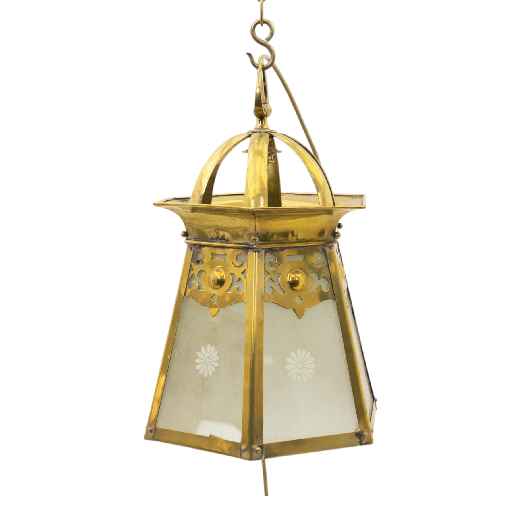 Arts & Crafts brass hall lantern, circa 1900, of hexagonal tapering form with open dome top support and pierced foliate detail above frosted glass panels with flower head detail, H41.5cm D29cm