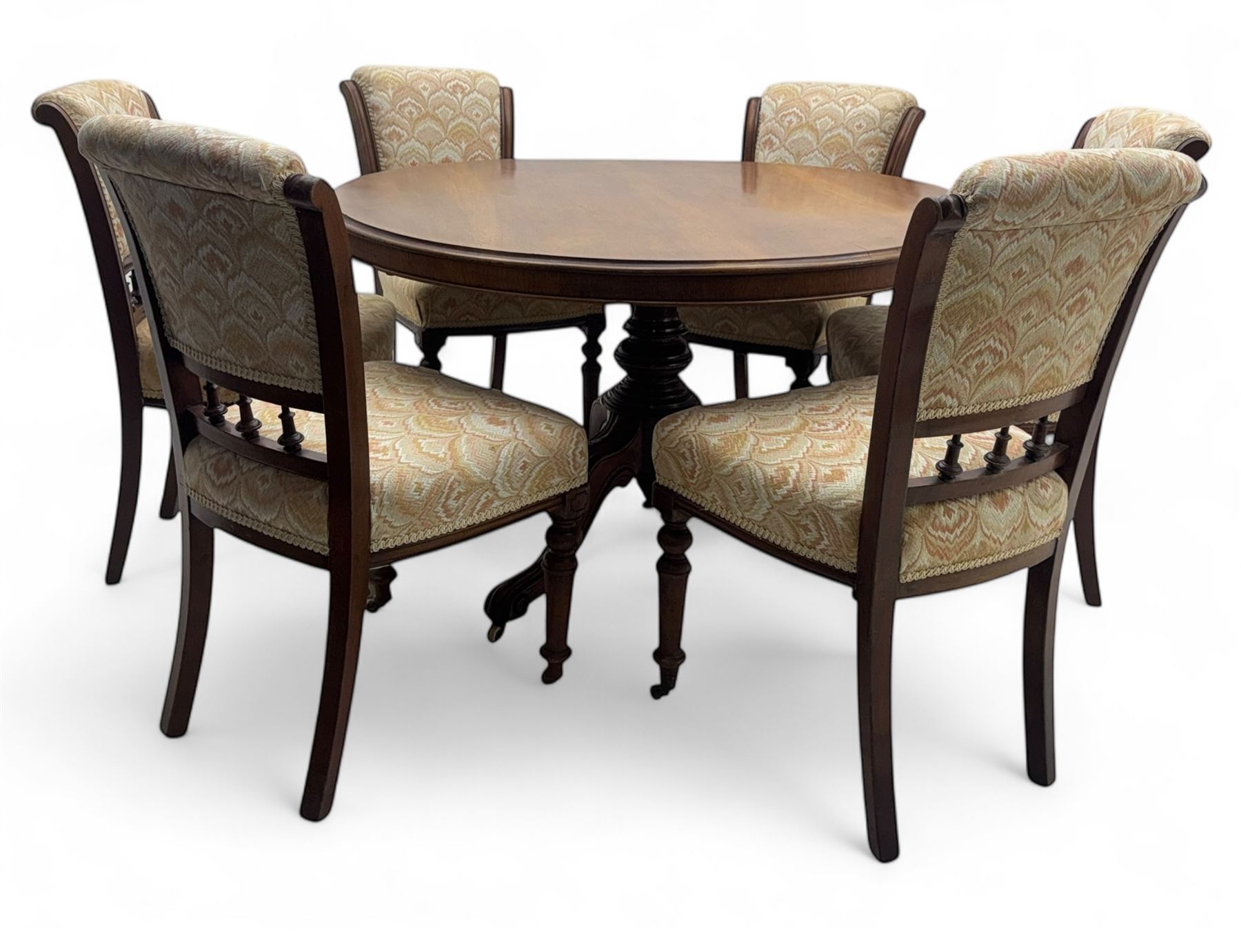 Victorian mahogany centre table, circular top above turned pedestal, terminating on three cabriole legs with scroll feet on porcelain castors, and six scroll carved upholstered dining chairs, with cushion and spindle turned backs, centre table  118x74cm, dining chairs 89x46x50cm
