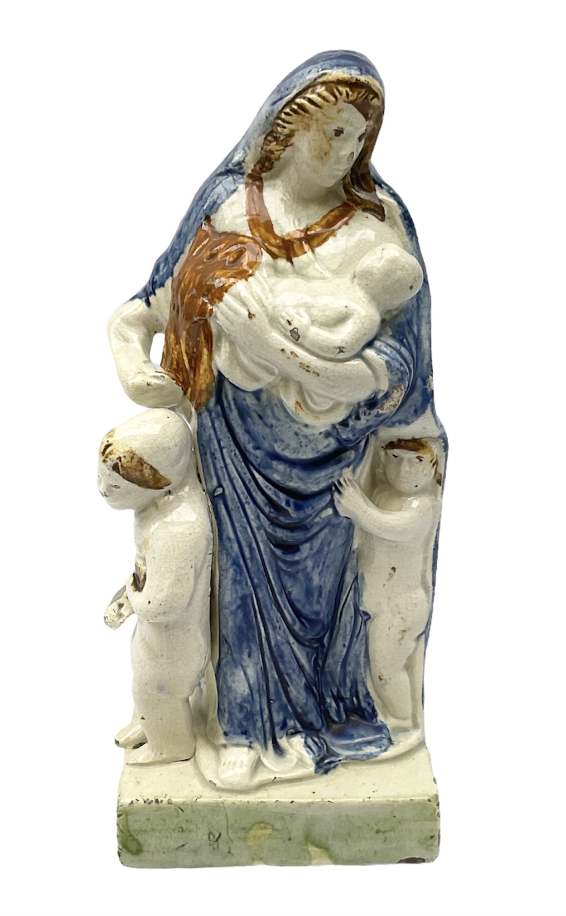 Late 18th century Prattware figure representing Charity, modelled as a mother with baby in her arms and two small children clutching at her robes, upon a square base, overall H21cm.