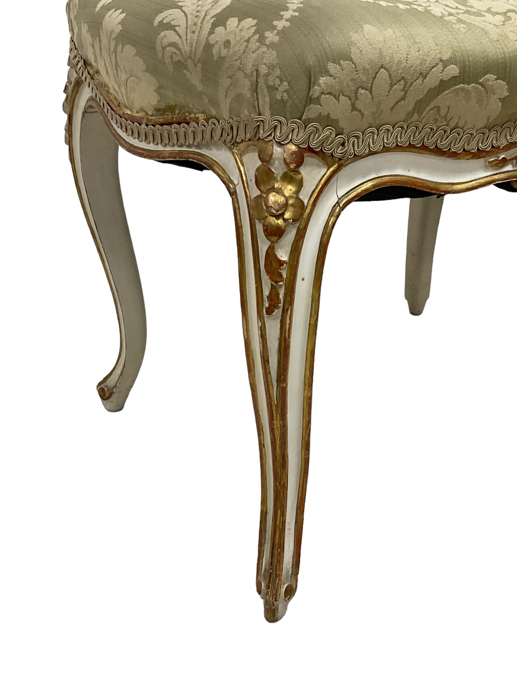 20th century French design parcel gilt and painted dressing table stool, upholstered in sage green damask fabric, shaped form on floral carved cabriole supports, with matching cushion 