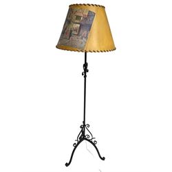 20th century wrought metal standard lamp, decorated with scrolls and on tripod base, with conical shade depicting hunting scene (H172cm); and a wrought metal wall hanging flower pot holder (W92cm)