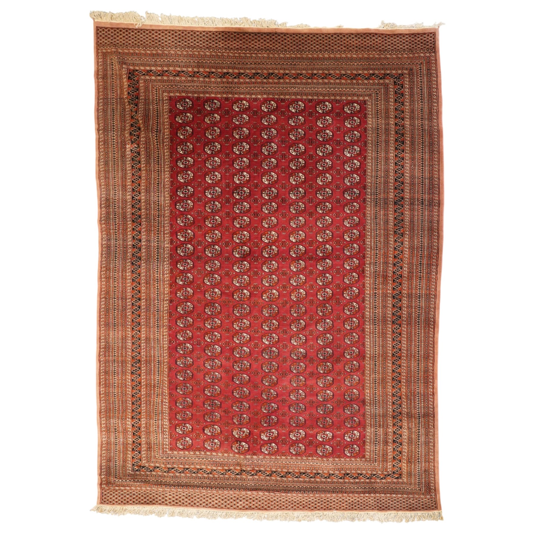 Large Afghan Bokhara crimson ground carpet, the field with rows of repeating Gul motifs and geometric design, enclosed by multiple repeating geometric guard bands