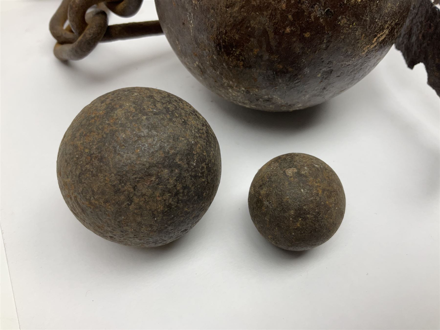 Late 19th/early 20th century prisoners iron ball and chain, with leg manacle; small cannon ball and grape shot