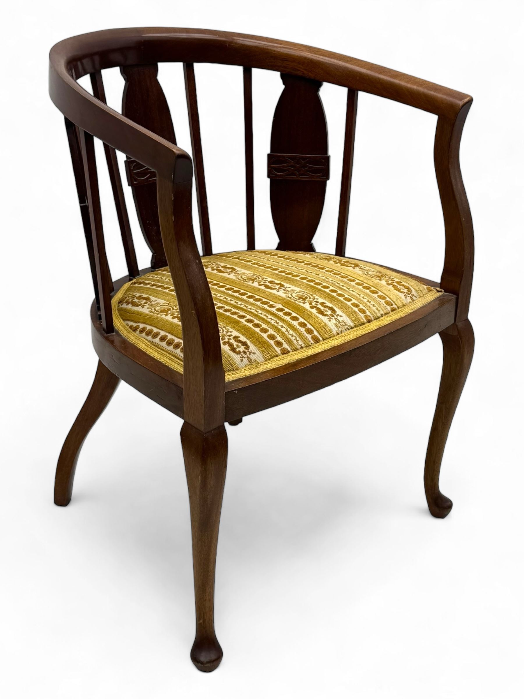Late Victorian mahogany framed tub chair, rounded backrest with vertical splats and three carved oval medallions, upholstered seat in yellow patterned fabric, on cabriole supports