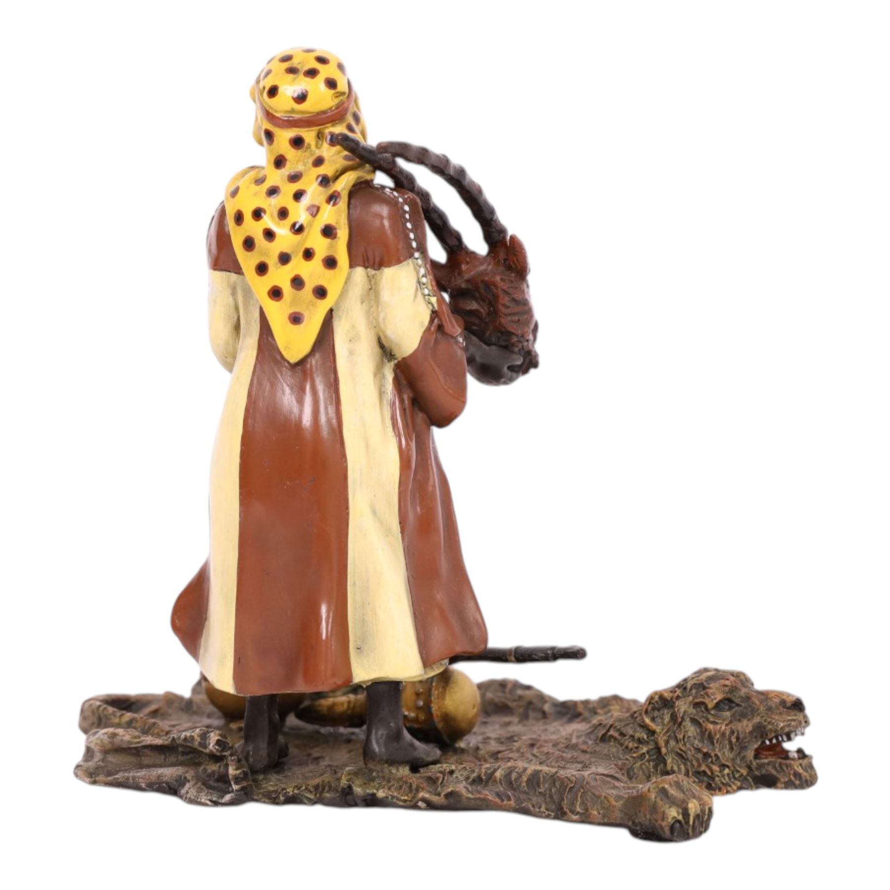 After Bergman - bronze Arab trader holding an antelope head while standing on a tiger skin, with a rifle and jars at his feet, H14cm