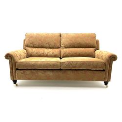 Duresta two seat sofa upholstered in a dark beige floral patterned fabric, raised on turned supports and castors 