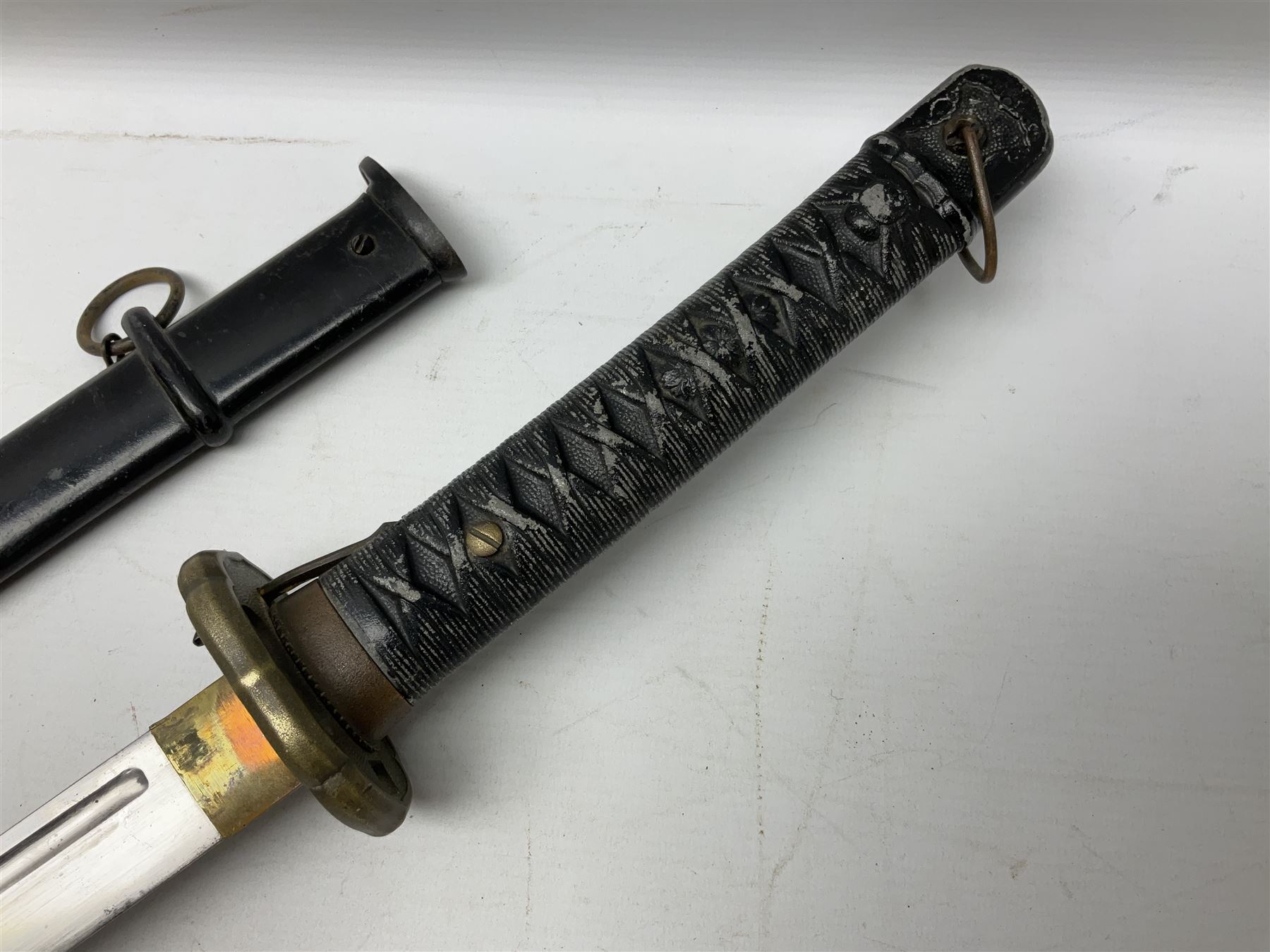 WW2 Japanese Army NCOs sword - katana, the 69.5cm slightly curving fullered blade numbered 14656; arsenal markings stamped near the habaki on the handle; brass tsuba and black painted metal hilt cast to simulate cord bound fish skin; in black painted steel scabbard with single suspension ring L96cm overall