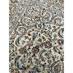 Persian Kashan ivory ground carpet, central pole medallion surrounded by swirling leafy branches and stylised plant motifs, scrolled foliate spandrels, the main border decorated with scrolling pattern and repeating palmettes, within floral patter guard stripes 