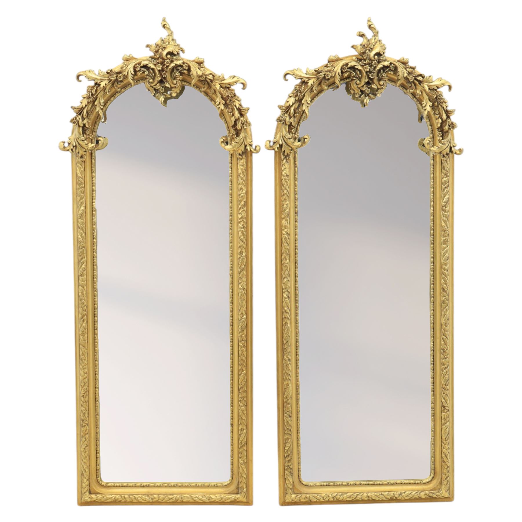 Pair of Louis XV style giltwood overmantel mirrors, the arched rectangular frame surmounted by an elaborate pierced cresting of acanthus scrolls, rocailles and floral swags, the moulded frame with continuous foliate carving and beaded inner slip