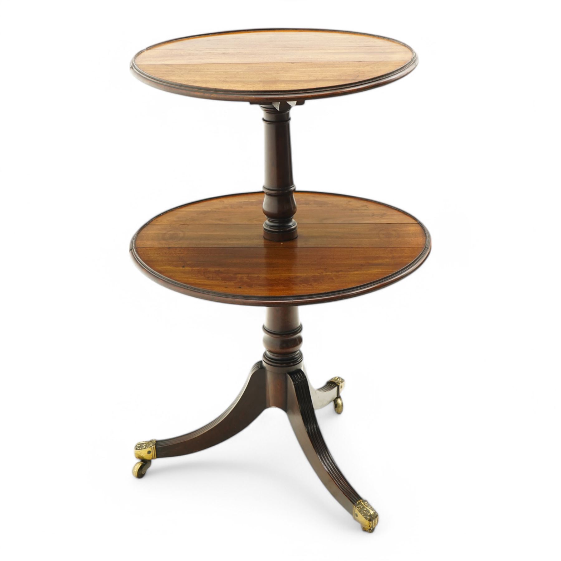 George III mahogany dumb waiter, two graduating drop-leaf tiers with moulded edges and raised lip surrounds, fitted with hinged stays, on turned columns and tripod base, three reeded out-splayed supports with ornate cast brass cups and castors, diameter 53& 59cm 