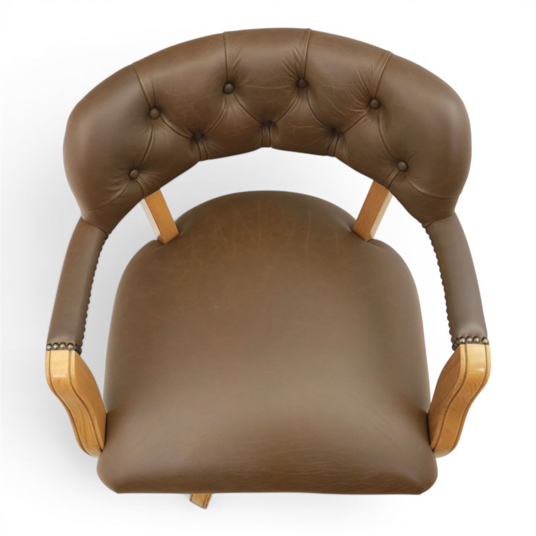Captain's swivel desk chair upholstered in buttoned tan leather, button backed chair rail, padded and downswept arms, raised on a six point base with castors