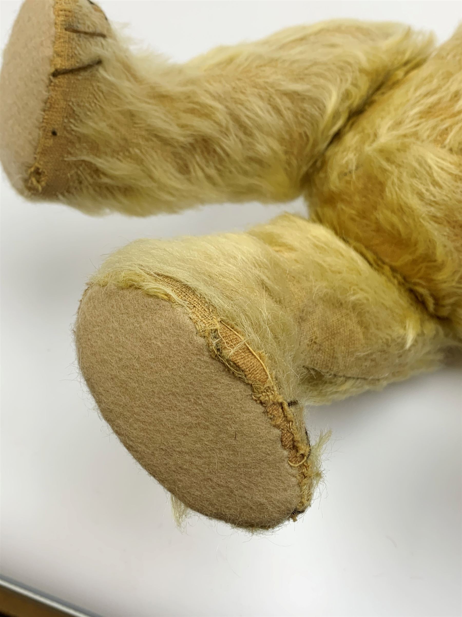 1930s teddy bear, possibly Farnell, with wood wool filled blond mohair body, the revolving head with original clear glass eyes, shaved muzzle with vertically stitched nose and mouth and jointed limbs with five-stitch claws H18.5