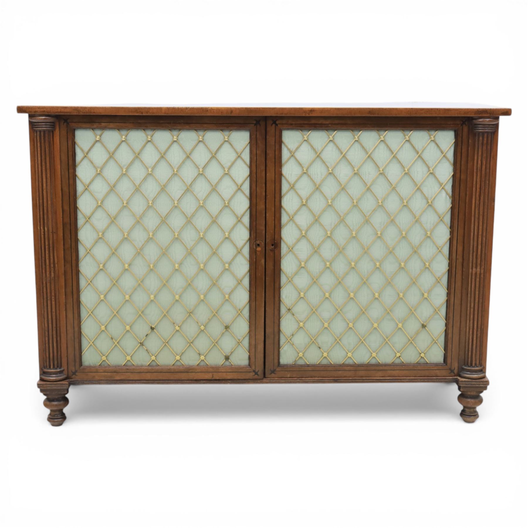 Late 20th century Regency style mahogany side cabinet, the rectangular crossbanded top with ebonised line inlay, above a pair of brass lattice grille doors with pale green fabric backing enclosing a shelved interior and two frieze drawers, flanked by reeded corner pilasters, upon turned tapering feet