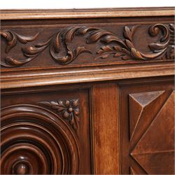 Late 19th century French walnut double bedstead, the panelled headboard with curling foliage carved frieze over concentric turned roundels and faceted mounts, lion mask carved rails with applied panelled mounts, matching footboard with lower carved lion mask 