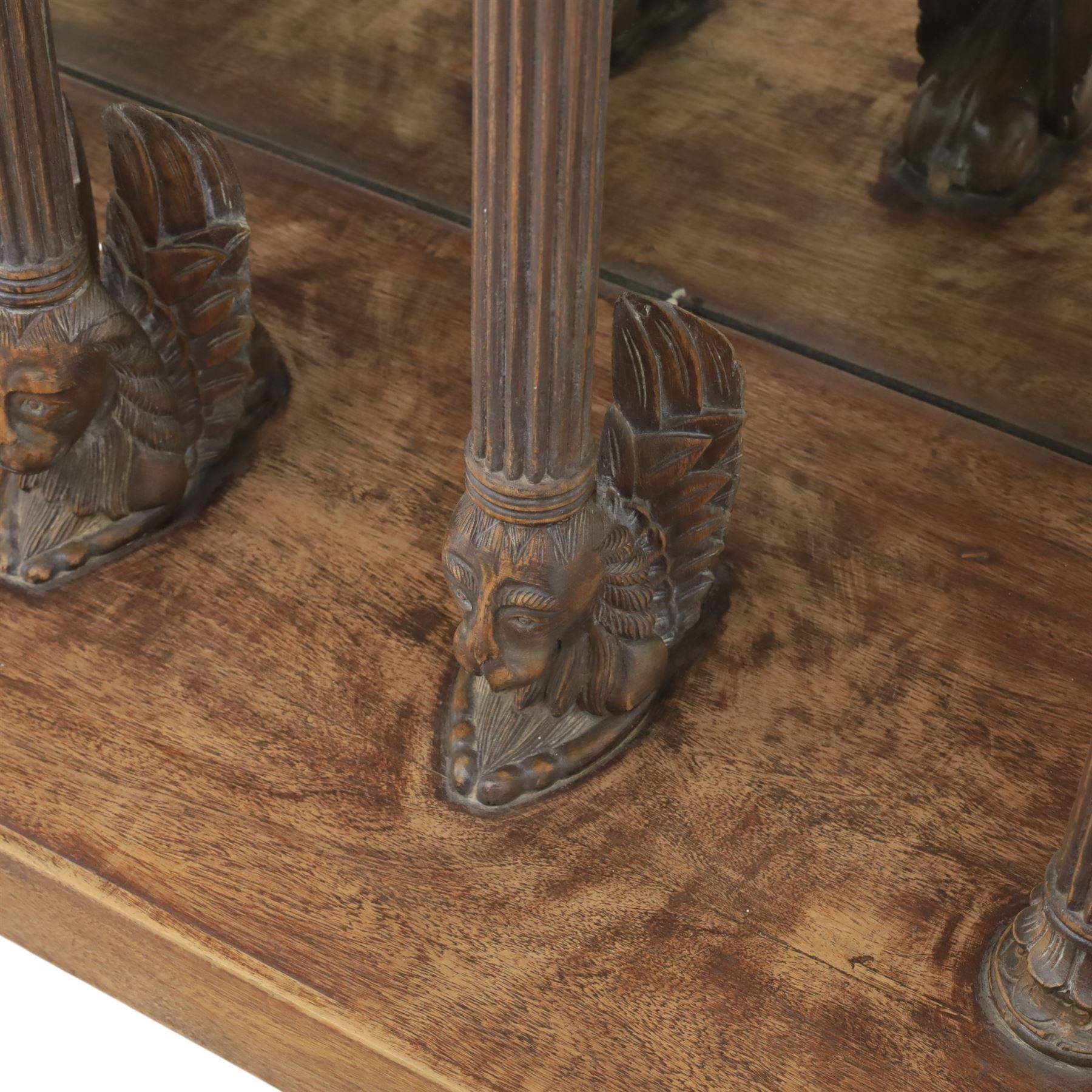 20th century carved hardwood console table in Renaissance taste, moulded marble slab top over a frieze decorated with festoons and roundels, the angles carved with grotesque mask brackets, supported by six fluted columns with carved mask and paw feet terminals, on a stepped plinth base with mirrored back