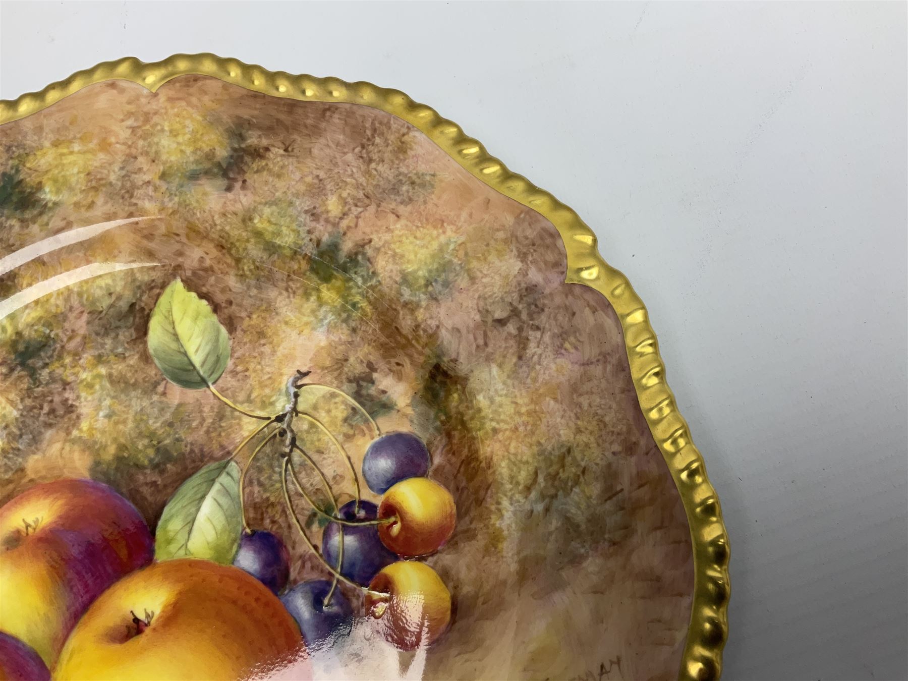 Mid 20th century Royal Worcester cabinet plate decorated by John Freeman, of circular form with gilt shaped rim, hand painted with a still life of fruit upon a mossy ground, signed Freeman, with black printed mark beneath, D27cm