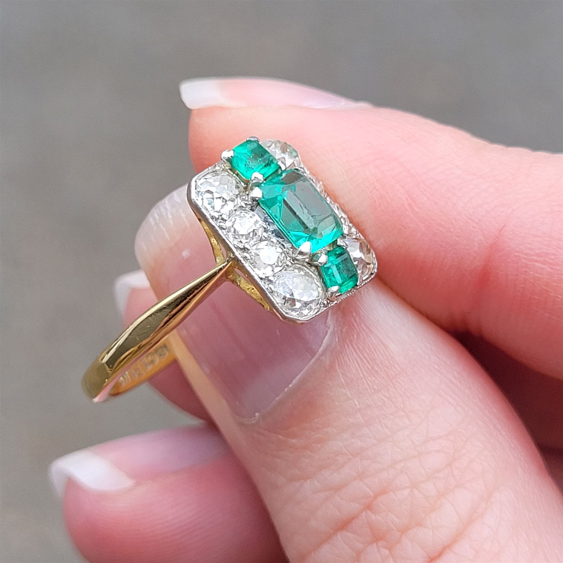 Early 20th century gold emerald and diamond panel ring, three octagonal cut emeralds, with four old cut diamonds set either side, stamped 18ct Plat, total diamond weight approx 0.85 carat