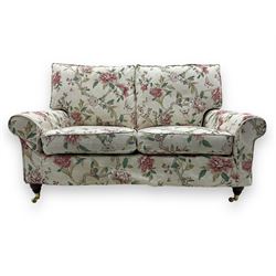Steed Upholstery - 'Knightsbridge' two seater sofa, upholstered in cream fabric with pink and green floral design, loose back and seat cushions, raised on mahogany supports with brass castors