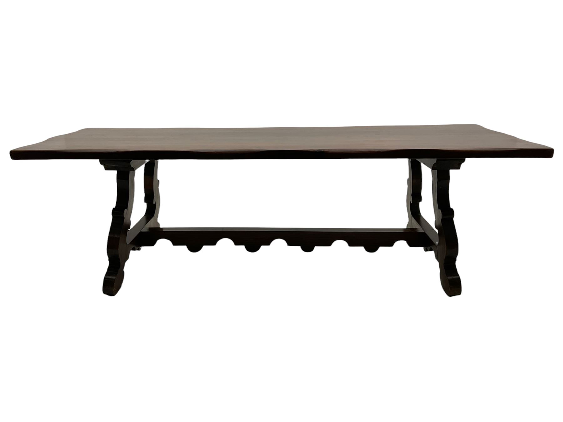 Large Spanish hardwood dining table, on shaped open ends supports joined by stretcher 

