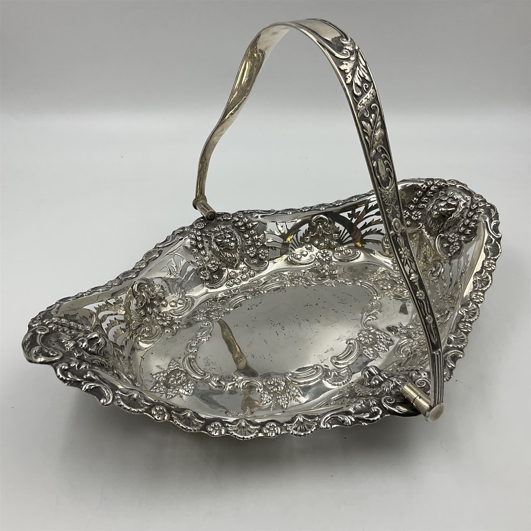 Edwardian silver swing handled basket, of navette form, with four repousse lion masks to each corner and with pierced and embossed floral, scroll and shell decoration to sides, base and handle, hallmarked Charles Horner, Birmingham 1906, height including handle H20cm