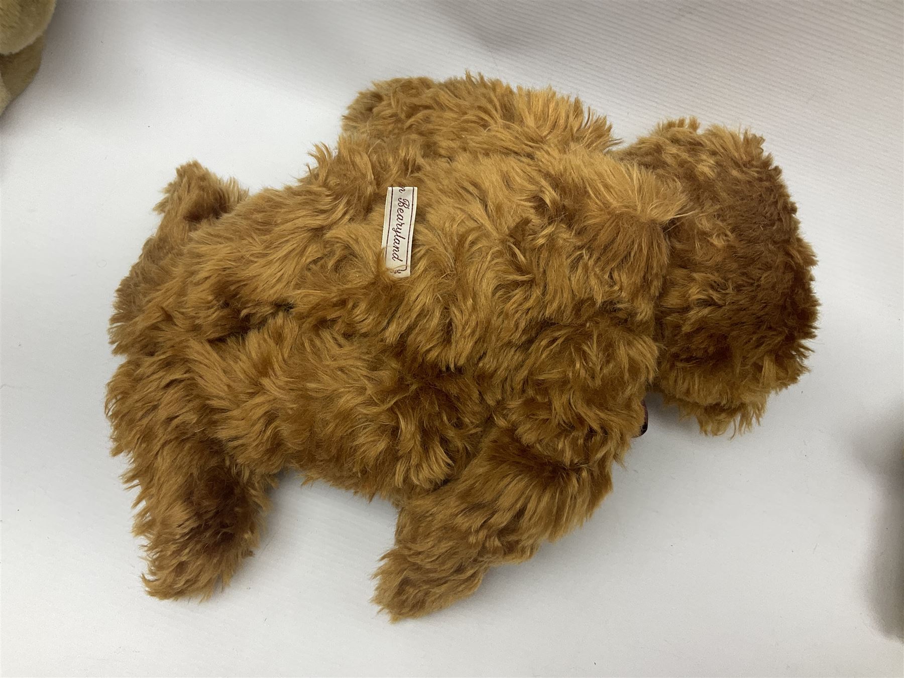 Group of five teddy bears comprising ‘George’ a unique pellet filled bear with glass eyes and velvet paws H38cm, and ‘Abbey’ a luxury German plush with wobble head and glass eyes no.5/10 H24cm, both with Teddies from Bearyland labels; along with two light blonde mohair H. M. Bears and Boyds Bears ‘T. F. Wuzzies’ no. 595140 (5)