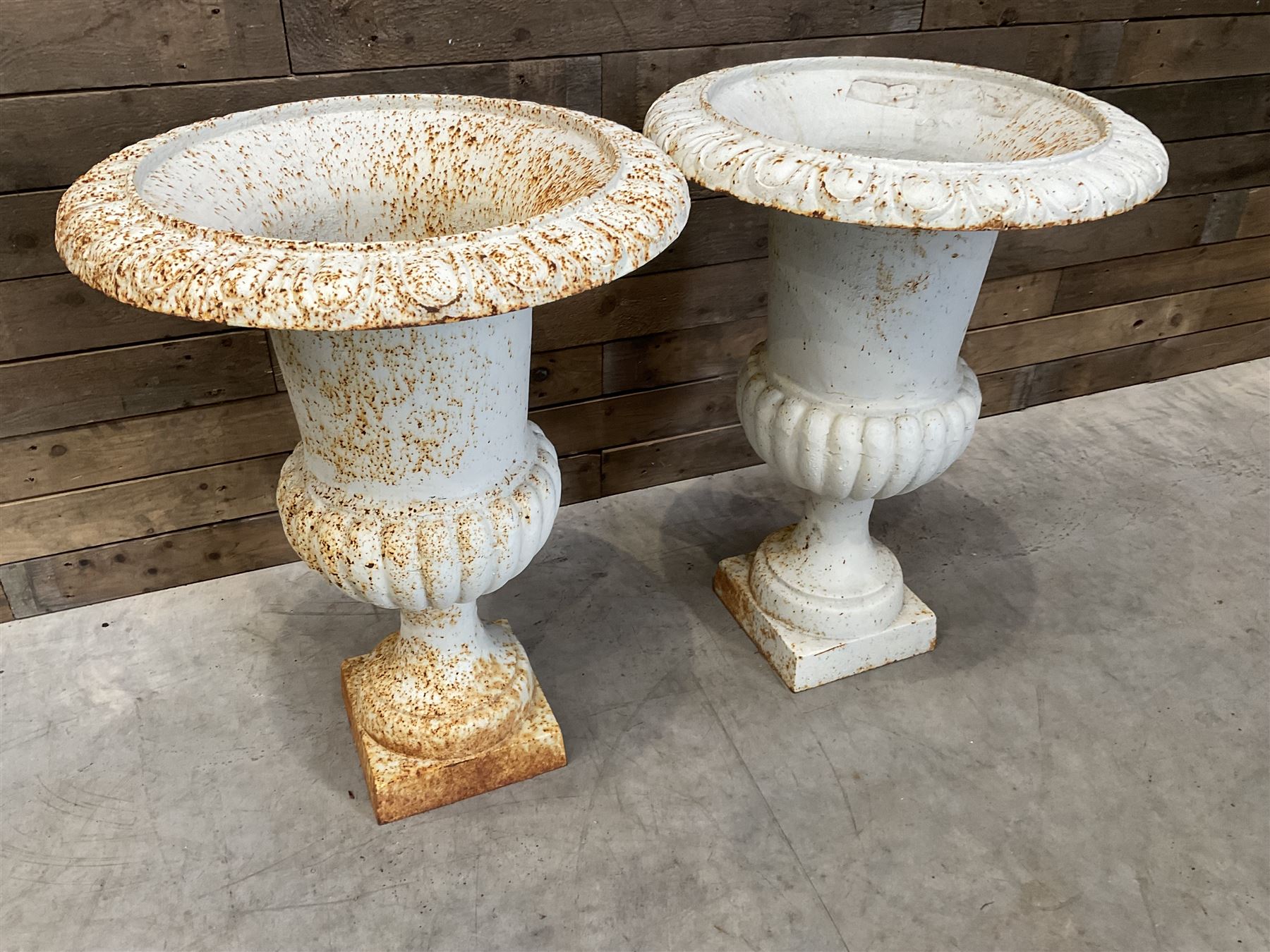 Pair of large Victorian design white painted cast iron campana shaped garden urns, egg and dart rim over a gadrooned underlobe, tapering column on square plinth base