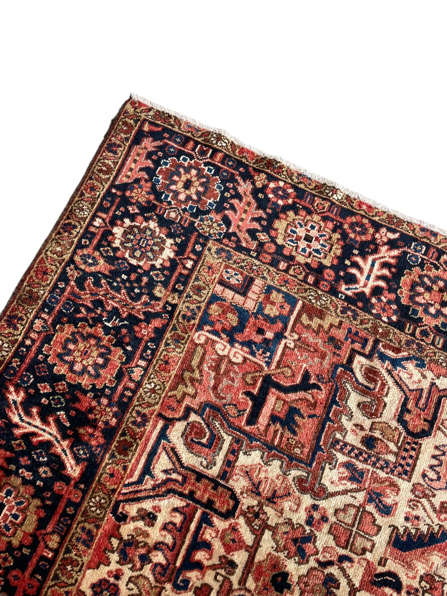 Persian Heriz red ground carpet, large stylised pole medallion surrounded by Pitrak motifs, indigo ground border decorated with stylised flower heads and trailing leafy branches, within floral pattern guard stripes