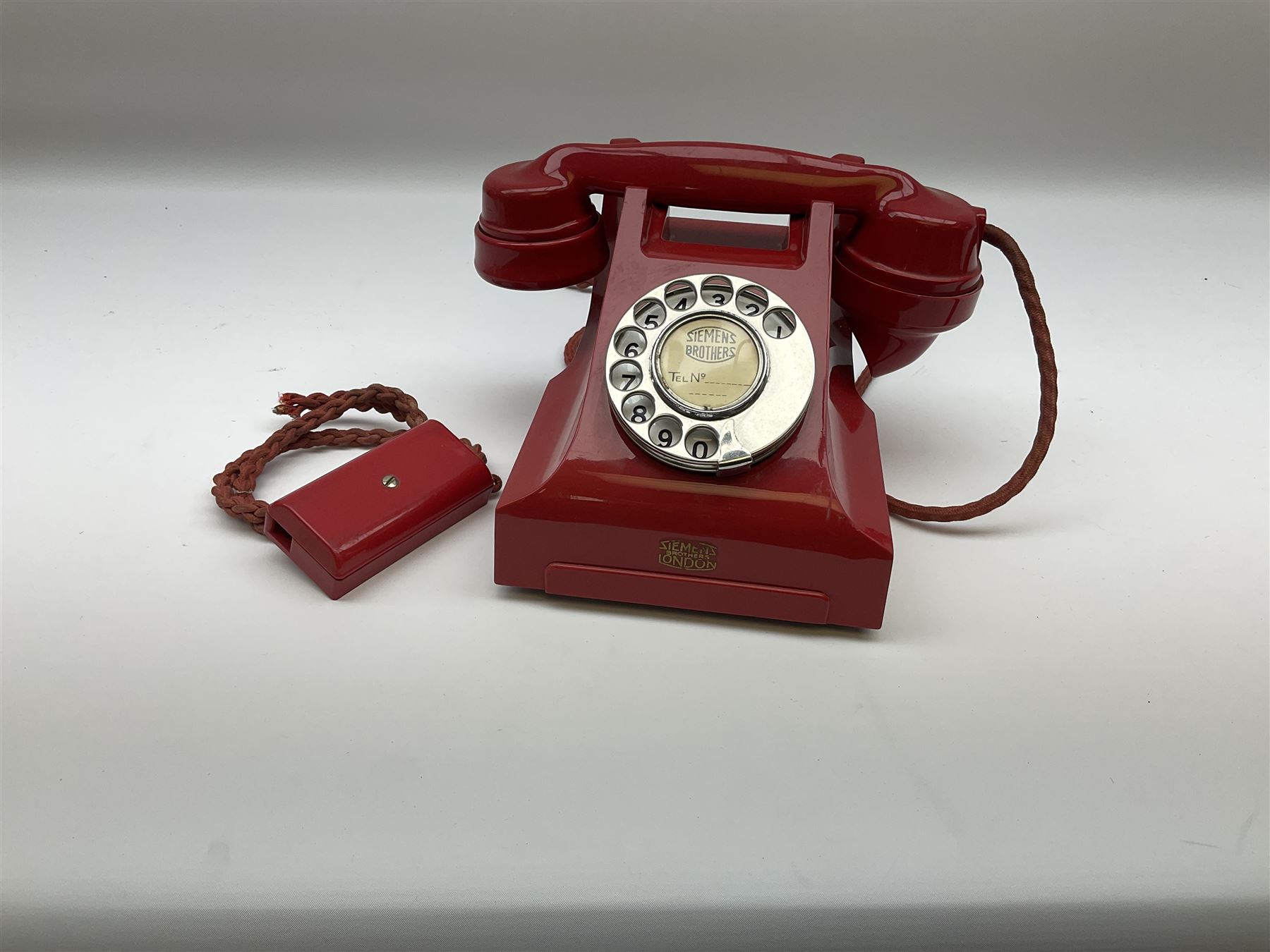 1950s Siemens Brothers red telephone with chrome rotary dial with enamel number plate and Siemens dial label, model 356, the body with base drawer below gilt logo, the handset with impressed mark PAT. 328926 PAT. SA 9/30, with red braided cord and red junction box (detatched), W15cm D18.5cm H14cm