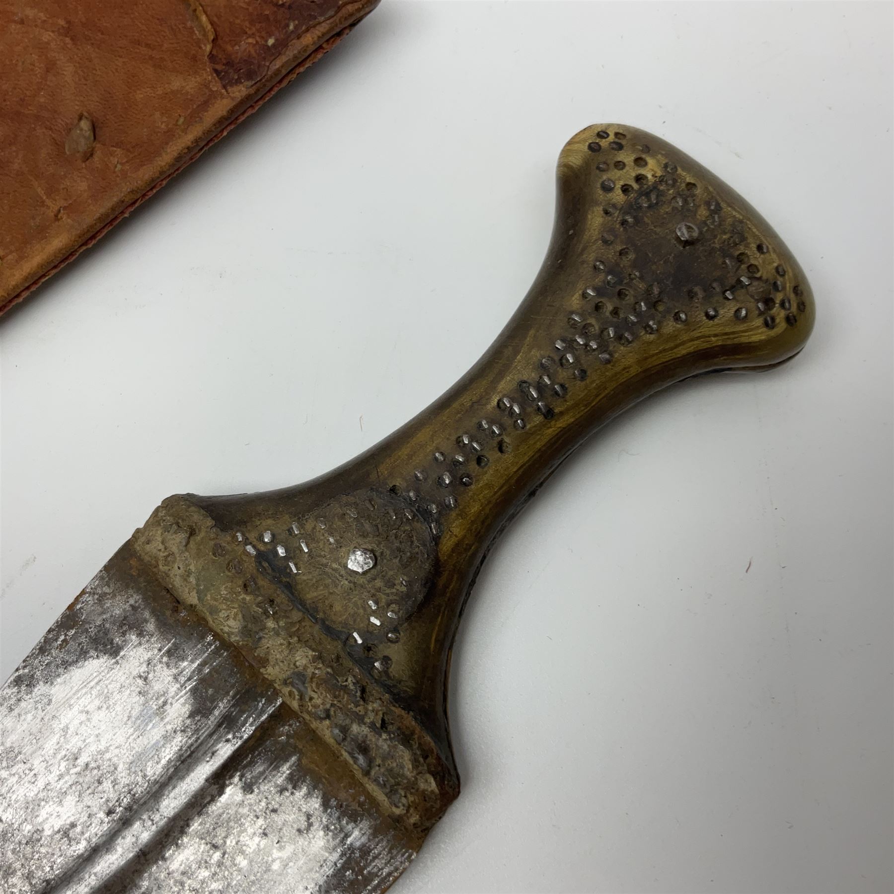 Late 19th century Yemeni Tuza jambiya as worn by religious elite, the 20.5cm curving blade with raised medial ridge, the horn hilt with pique style studwork, in a leather wrapped wooden scabbard with pierced metal mount and leather belt applied with embroidered 'gold' and 'silver' thread work panel; dagger L36cm overall, belt L84cm
