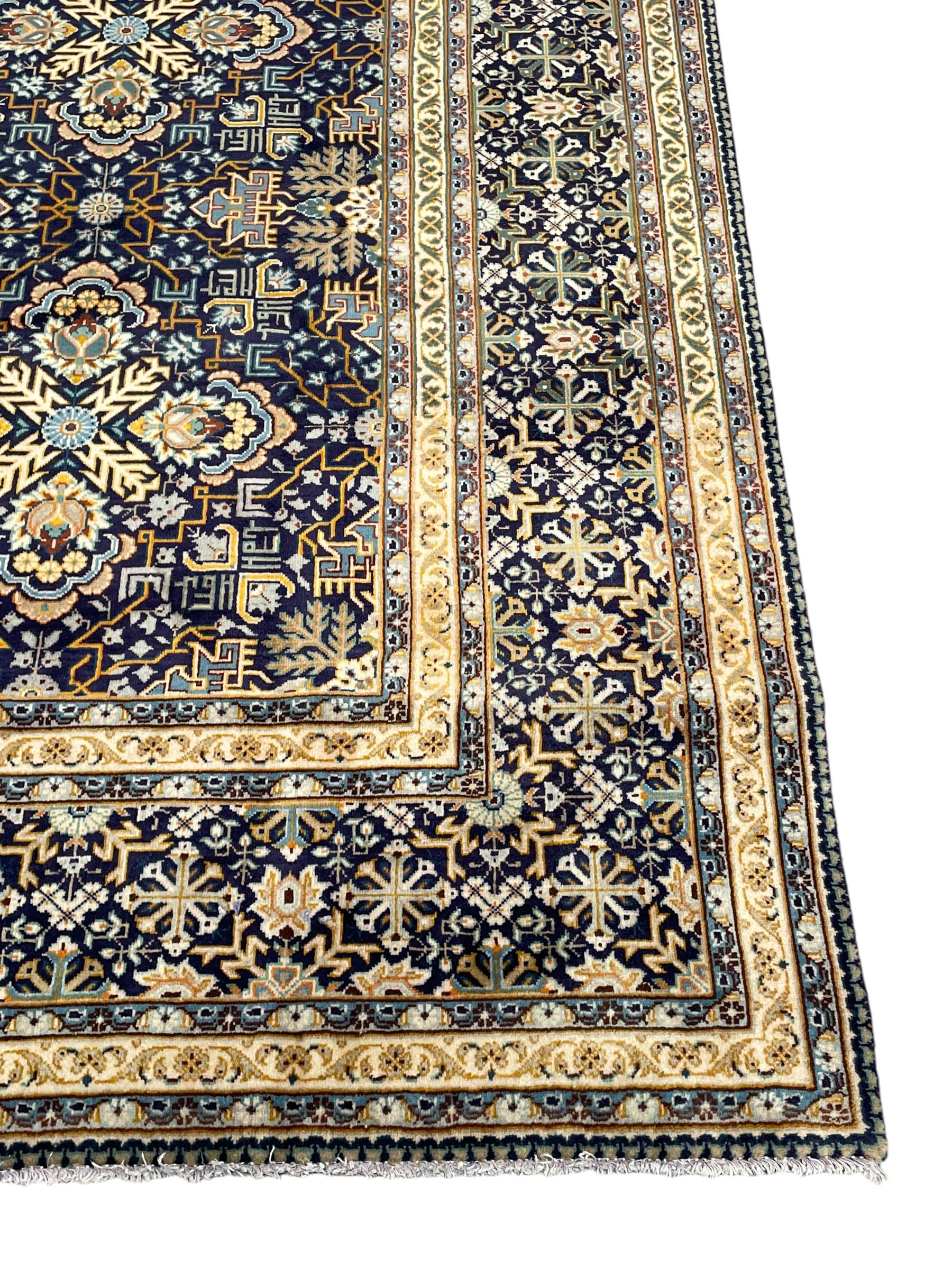 Persian indigo and pale gold ground rug, overall busy geometric design, the field decorated with hooked Hac and palmette medallions surrounded by densely patterned zig-zags and stylised foliate motifs, the border decorated with smaller Hac motifs, within multiple guard stripes 