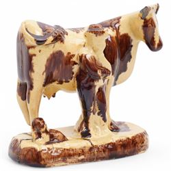 Early 19th century pottery model of a cow with drab colouring accompanied by a standing figure and a dog on naturalistic base, possibly South Yorkshire L14cm x H14cm
