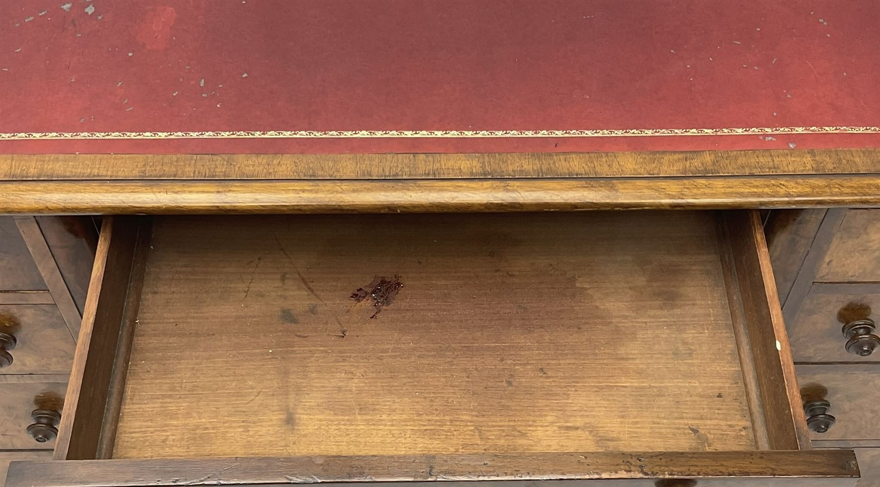 Victorian figured walnut kneehole desk, moulded rectangular top with inset leather writing surface, fitted with nine drawers, the central frieze drawer with carved curled foliage mount, on moulded plinth base,