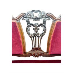 Late Victorian stained beech framed sofa, the backrests, seat and padded arms upholstered in deep red fabric, carved crest rail with scroll and foliate motifs supported by carved uprights, on cabriole supports with leaf carvings terminating in castors