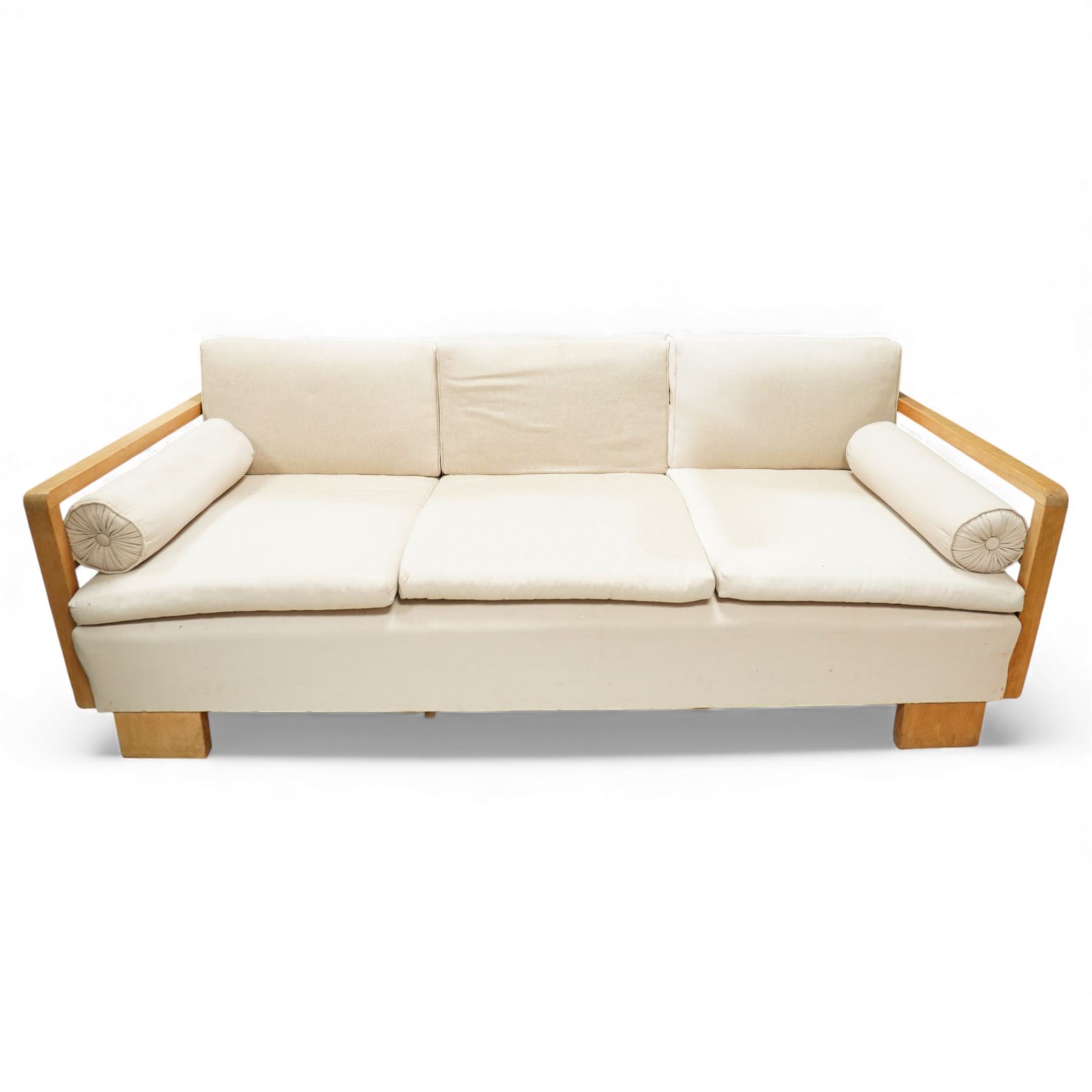 Mid 20th century German Art Deco oak framed divan day bed, rectangular form with slatted side supports, upholstered in cream linen with three removable back cushions, three seat cushions and cylindrical bolster arms, on block feet