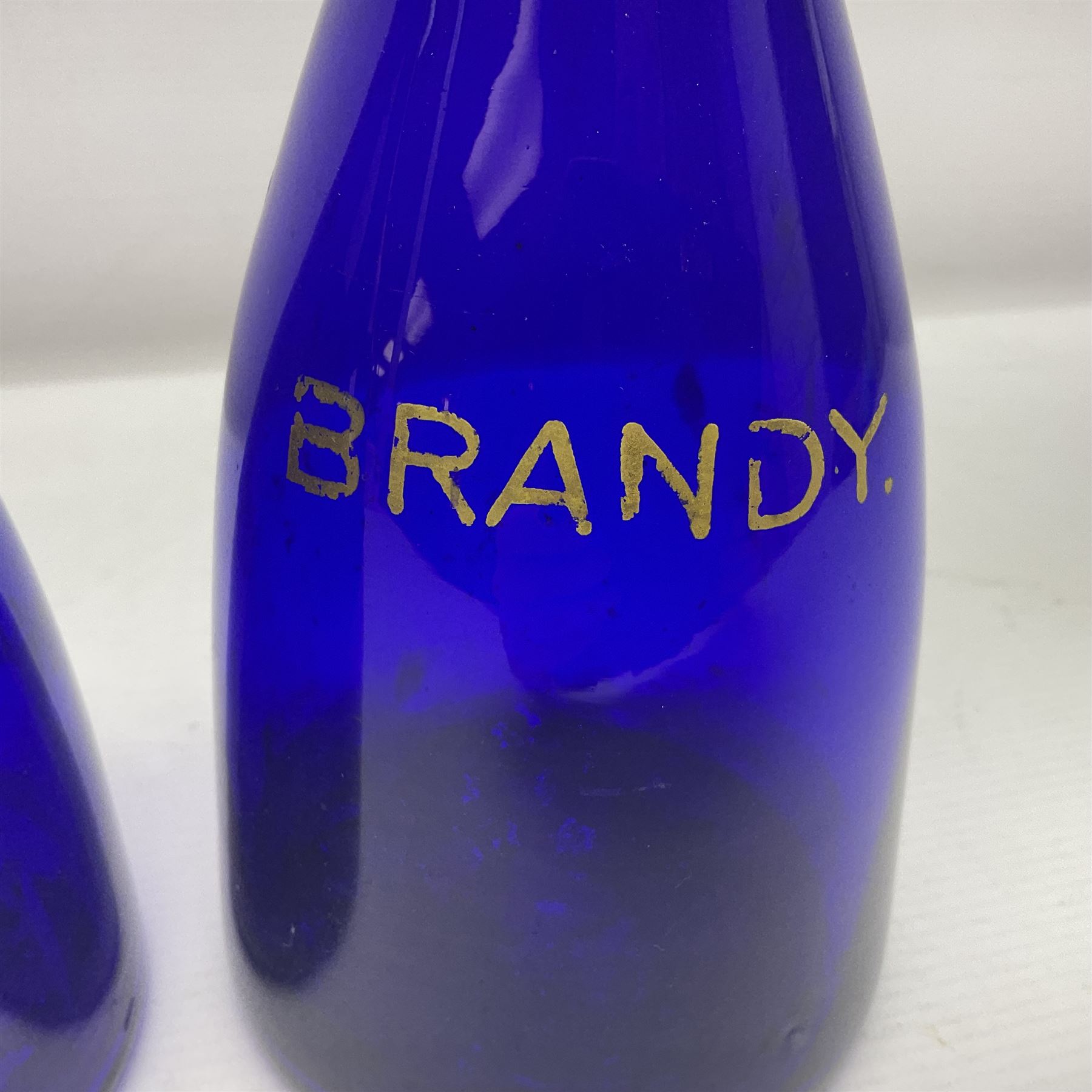 Pair of early 19th century blue glass decanters with teardrop stoppers, with gilt writing, the first marked Gin the second Brandy 