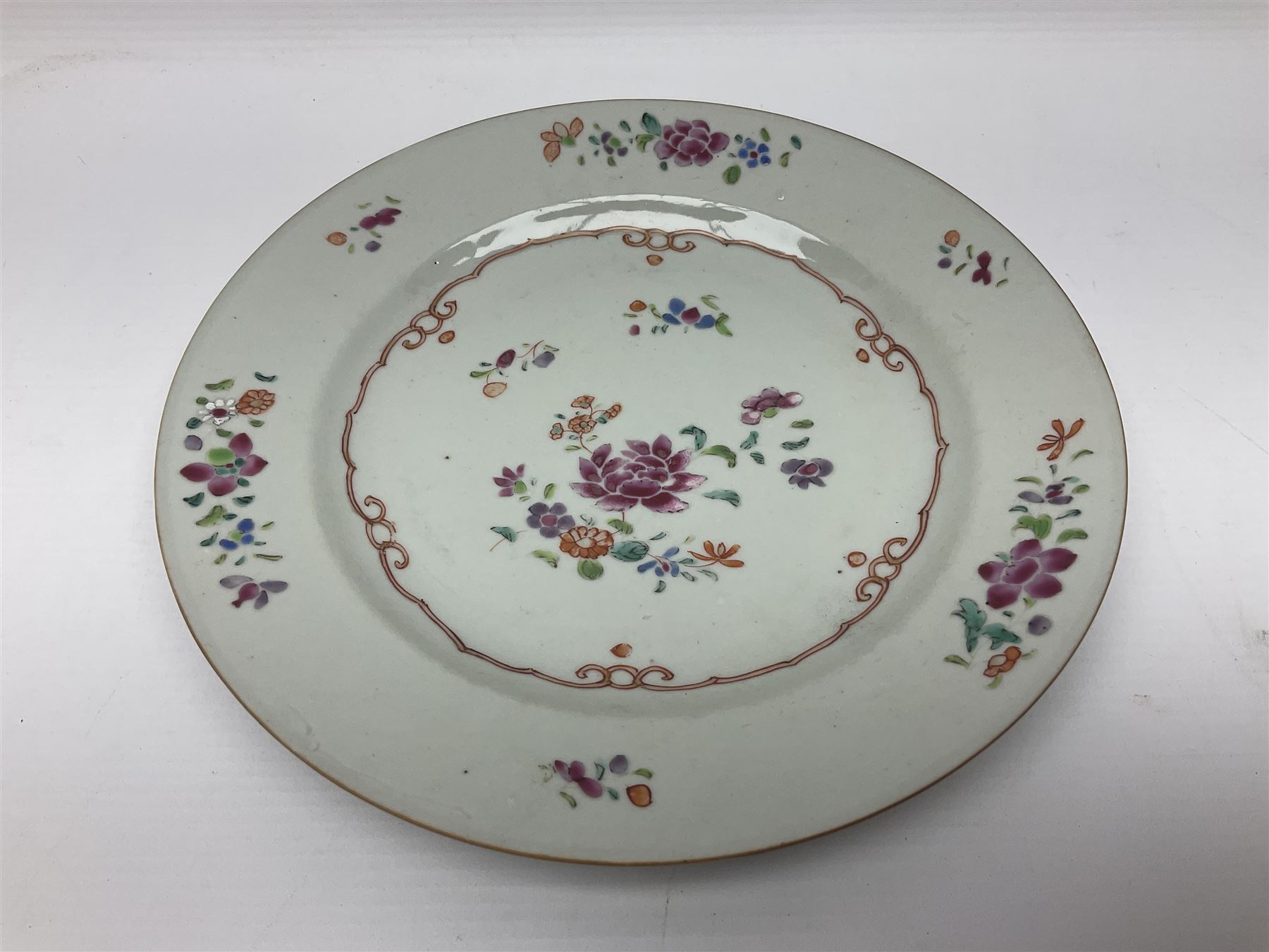 Three 18th century Chinese Famille Rose plates, the first example enamelled with blossoming peonies, rockwork and fence, the other two examples of similar design, decorated with blossoming peonies and sprigs within shaped inner borders, each approximately D23cm