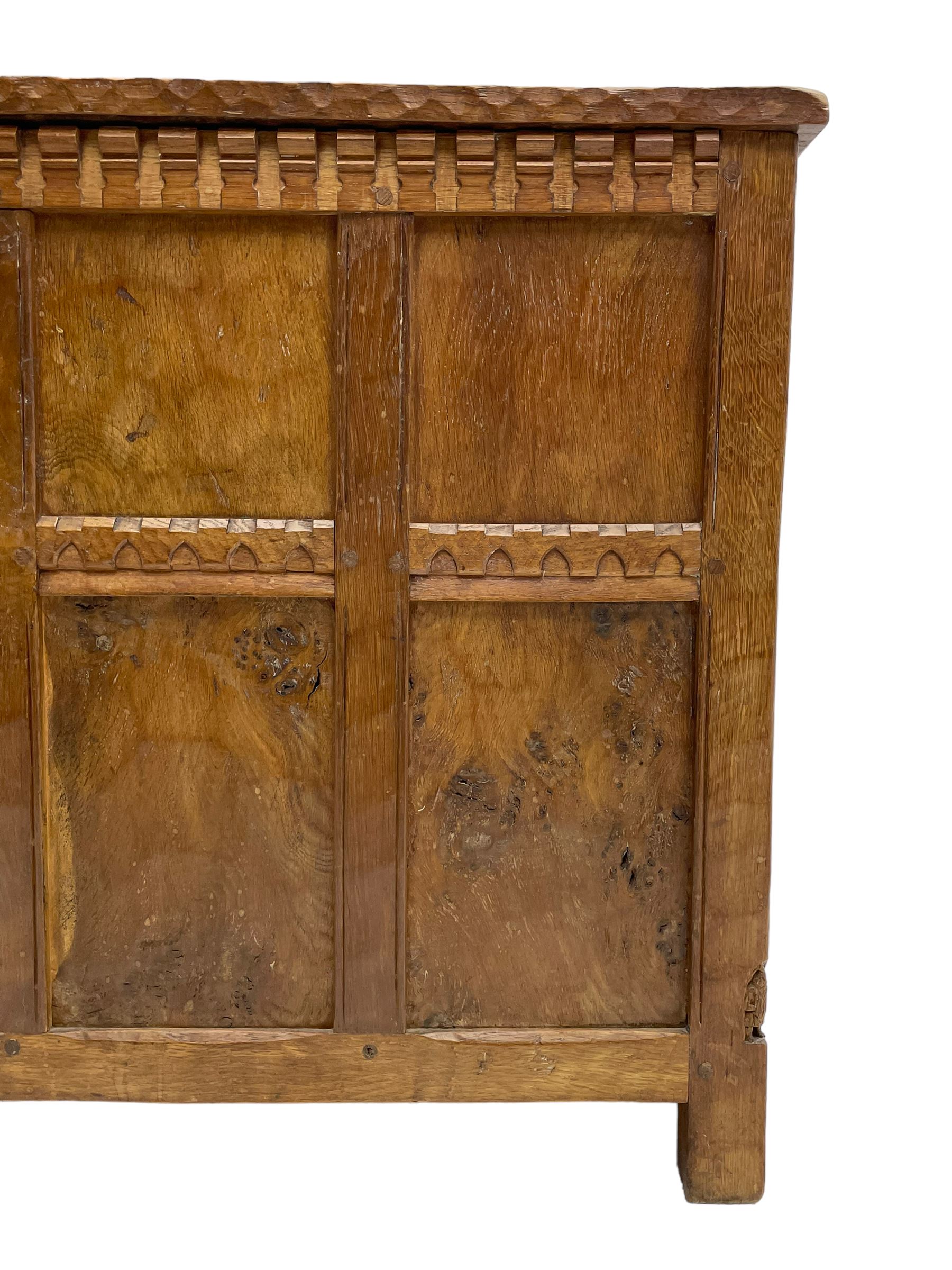 Gnomeman - oak blanket box, all-over adzing, the hinged top over figured and burr panelled front, decorated with carved crenellations and arcade, carved with gnome signature, pierced handles to each end forming the central rail, wrought metal hinges, on stile supports, by Tom Whittaker, Littlebeck, Whitby