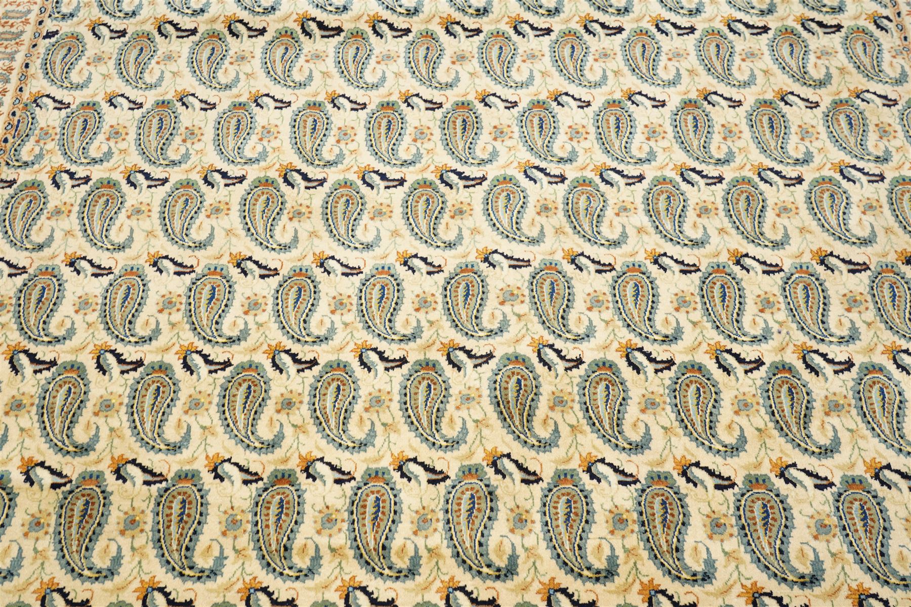 Central Persian Kashan hand-knotted carpet, ivory field densely decorated with all-over repeating botehs motifs, arranged in rows and enclosed by scrolling vine work and floral sprays, in a palette of indigo, pale blue, sage green and muted terracotta tones, within ivory borders of small boteh motifs flanked by border within large scale boteh motifs with multiple guard stripes, with cotton fringe ends 