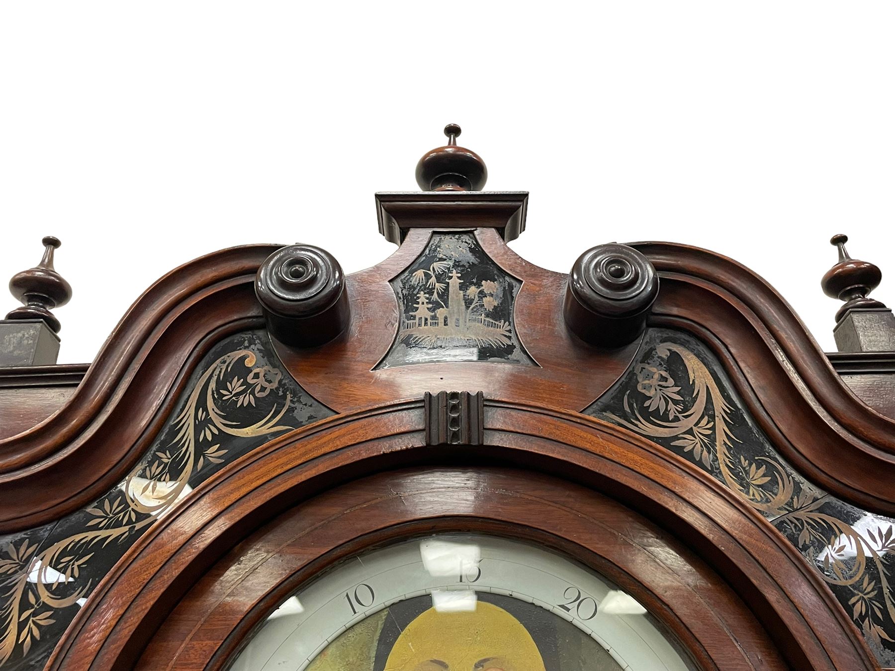 Penlington of Liverpool – early 19th century 8-day mahogany longcase clock, swans neck pediment with three turned wooden finials and verre eglomise panels, trunk with reeded columns and wavy topped door, plinth with canted corners on bracket feet, painted break-arch dial with Roman numerals and five-minute Arabic’s, centre sweep calendar and seconds hands, blue steel serpentine hands, signed beneath a painted rolling moon in the arch PENLINGTON, LIVERPOOL, eight day four pillar movement, anchor escapement and rack striking on a bell. With pendulum and weights.  The Penlington family were prolific clockmakers in 19th century Liverpool working from several addresses in the city, also recorded as chronometer and chronograph makers.