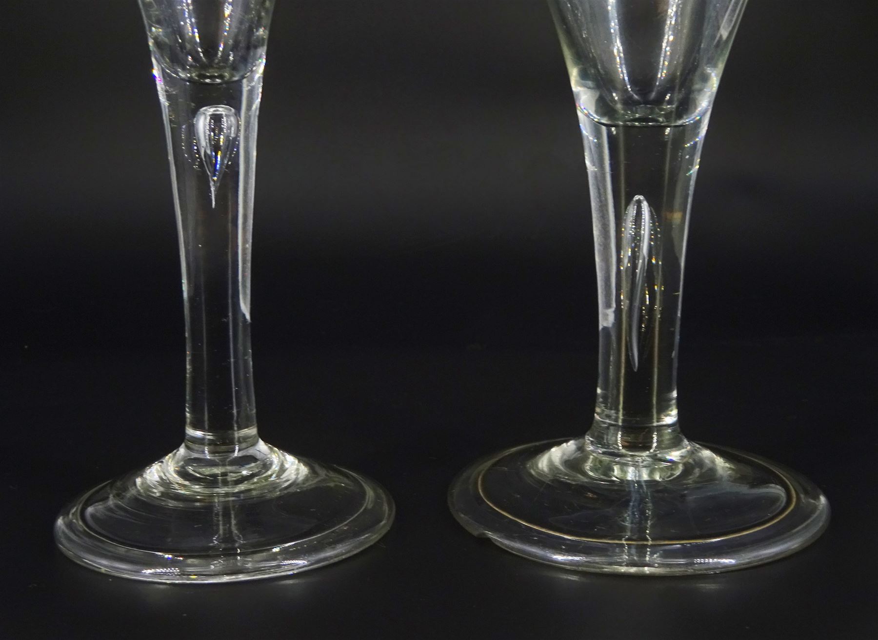 Two 18th century drinking glasses, the drawn trumpet bowls upon stems with internal tears, one elongated, and folded conical feet, largest H18cm