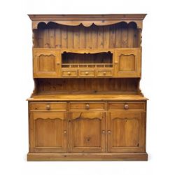 Traditional vintage pine kitchen dresser with scrolled cornice and rack with long shelf above a galleried shelf flanked by three short drawers and two cupboards, the base with three long drawers above three cupboards on plinth base  