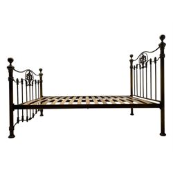 Victorian design king size brass bed frame, featuring an arched headboard and footboard with intricate cast floral and scrollwork centre motifs, flanked by cylindrical supports with ball finials and decorative collars, raised on rounded feet, with a slatted wooden base