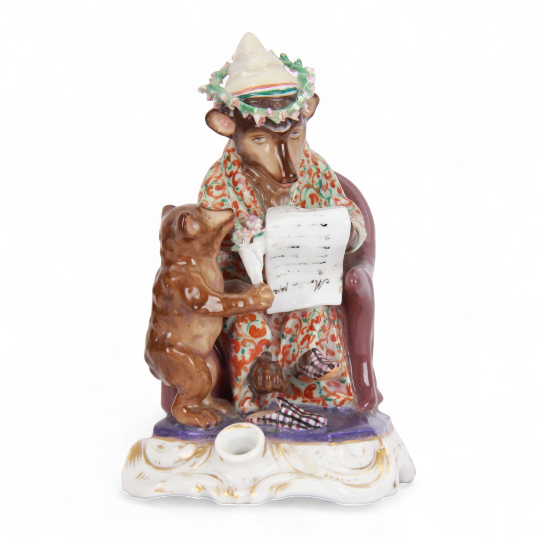 Mid 19th century French porcelain inkwell, possibly Jacob Petit, circa 1884, modelled as a anthropomorphic bear seated within an armchair, wearing cap, gown and slippers, reading a letter to a small cub holding a bunch of flowers, upon a shaped and scrolling base, impressed and incised marks beneath, H19cm

