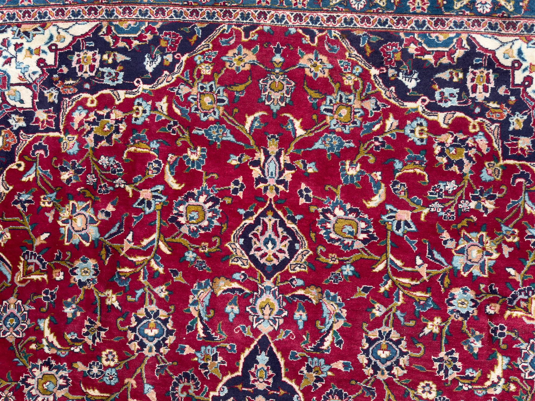 Pair of Persian wool rugs, each with rich red ground, one centred with a diamond-shaped medallion and navy spandrels within a floral field, the other with radiating floral medallion and scrolling foliate motifs, both enclosed by multiple borders with palmette and flowerhead designs, from the region of Kashan 291x376, 299 x 378 